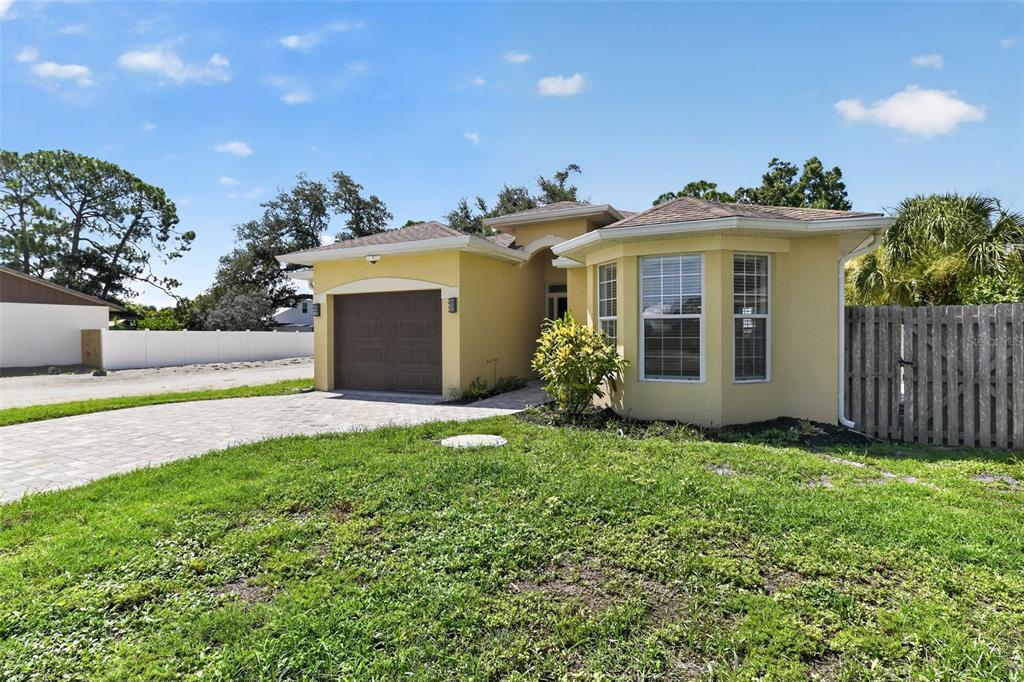 A yellow single-story house with a paved driveway, a garage, and a wooden fence — 1816 RITA STREET, SARASOTA, FL