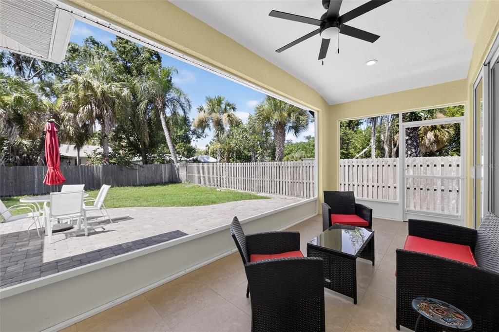 A screened-in patio features tile flooring, wicker furniture, a ceiling fan, and a fenced backyard — 1816 RITA STREET, SARASOTA, FL