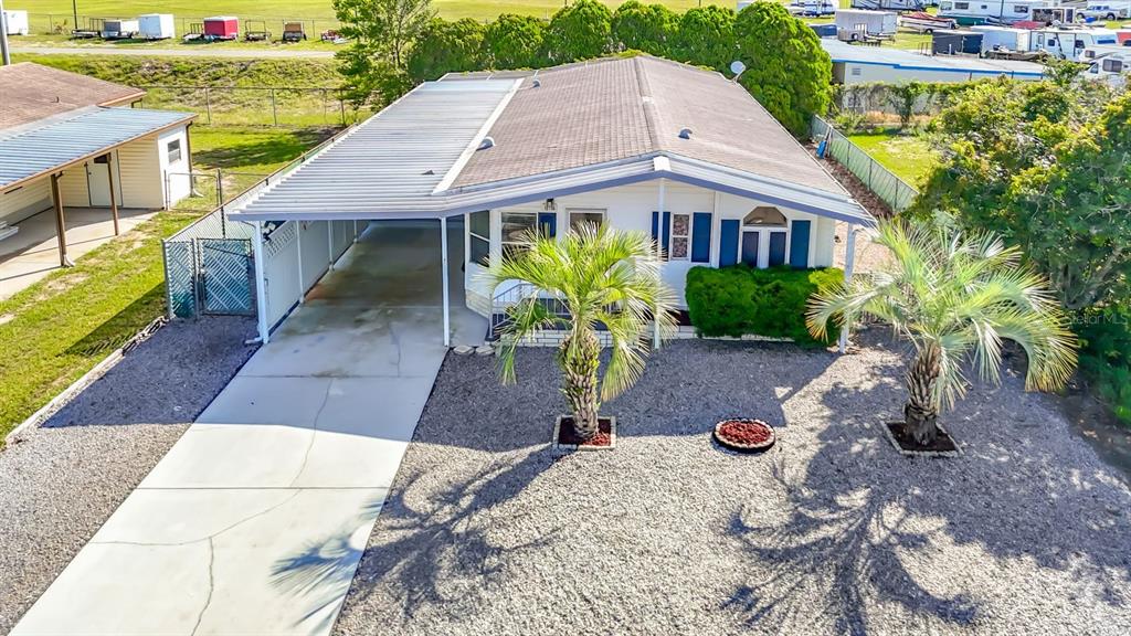 An aerial view shows a single-story house with a carport, gravel yard, and two palm trees — 15116 BROOKRIDGE BOULEVARD, BROOKSVILLE, FL