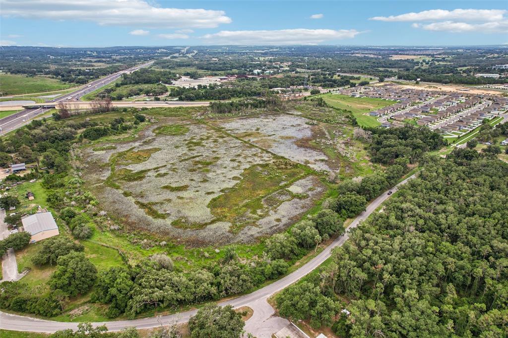An aerial view shows a large, undeveloped grassy field surrounded by trees and nearby roads — 20736 OBRIEN ROAD, GROVELAND, FL