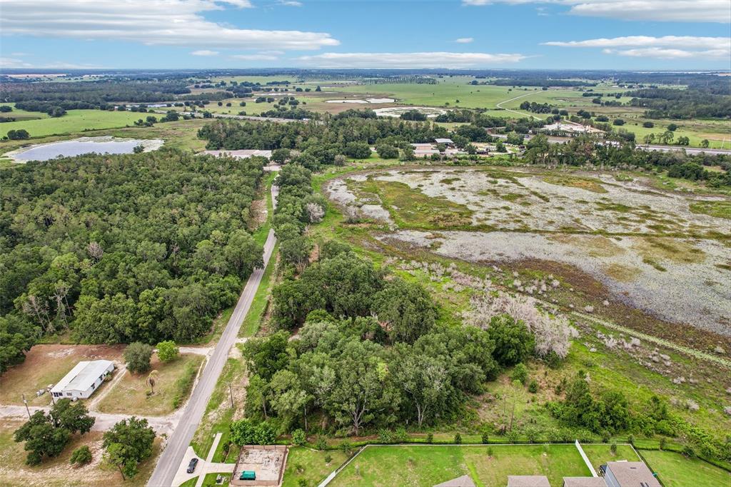 An aerial view shows a rural landscape with a road, dense trees, and a large wetland — 20736 OBRIEN ROAD, GROVELAND, FL