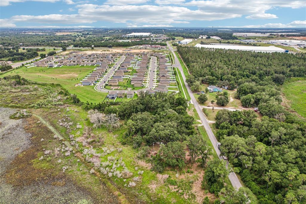 An aerial view shows a suburban neighborhood adjacent to a wooded area and a road — 20736 OBRIEN ROAD, GROVELAND, FL