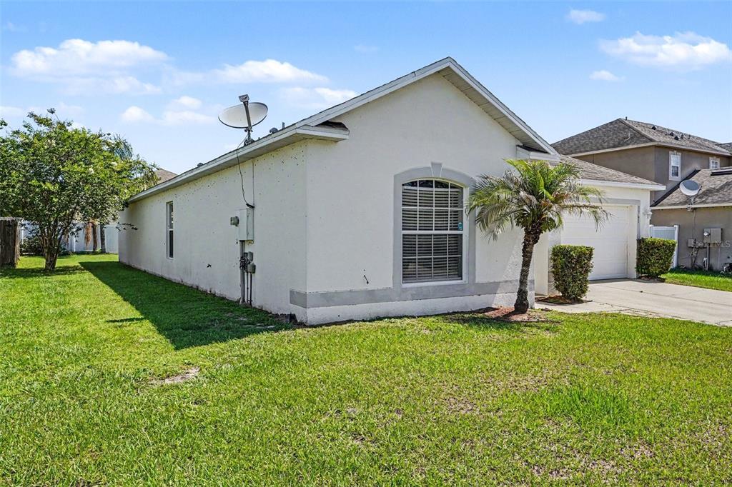 A single-story house with a white stucco exterior, a side-entry garage, and a grassy yard — 1761 EAGLE PINES CIRCLE, EAGLE LAKE, FL