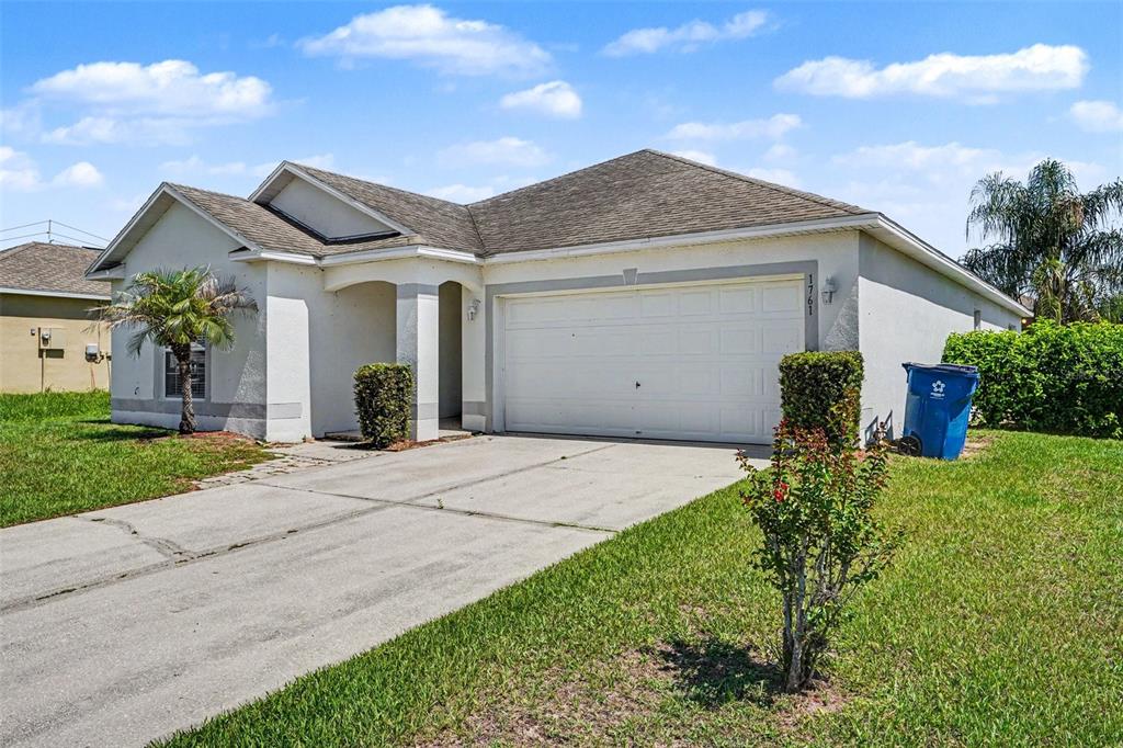 A single-story house with a white stucco exterior, a two-car garage, and a concrete driveway — 1761 EAGLE PINES CIRCLE, EAGLE LAKE, FL