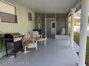 A covered patio features a grill, two chairs, and a screened-in area — 7391 HARLOW STREET, BROOKSVILLE, FL