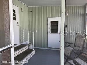 A covered porch features light green vertical siding, a white door, and a set of steps — 7391 HARLOW STREET, BROOKSVILLE, FL