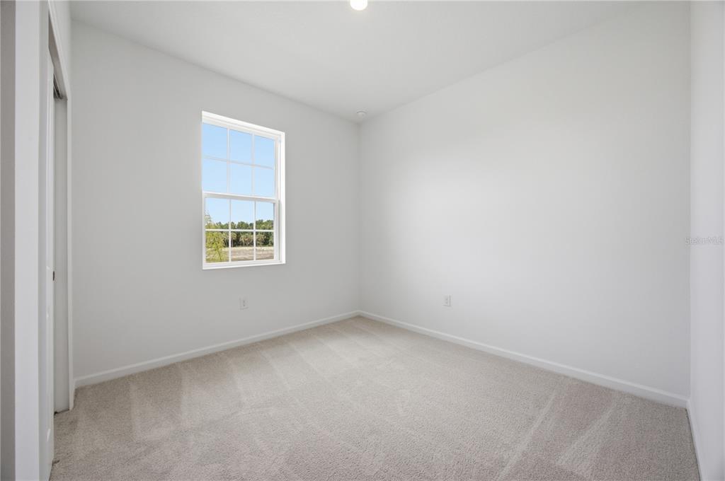 An empty bedroom with white walls, beige carpet, and a single window — 5727 HIAWASSEE ROAD, OKAHUMPKA, FL