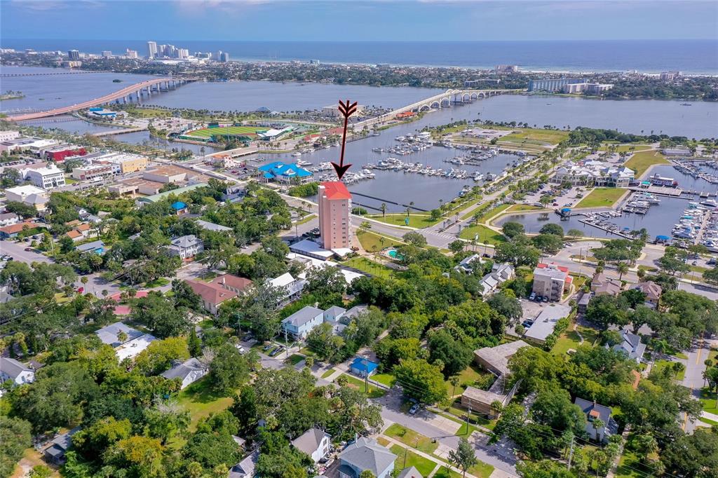 An aerial view shows a tall residential building with a red roof near a marina — 404 S BEACH STREET UNIT 503, DAYTONA BEACH, FL