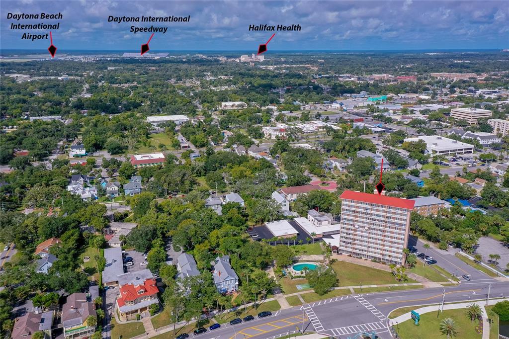 An aerial view shows a high-rise apartment building surrounded by trees and city streets — 404 S BEACH STREET UNIT 503, DAYTONA BEACH, FL