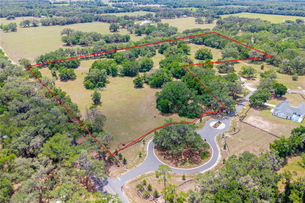 An aerial view shows a large, grassy, tree-dotted plot of land outlined in red — TBD SW 170TH STREET, NEWBERRY, FL