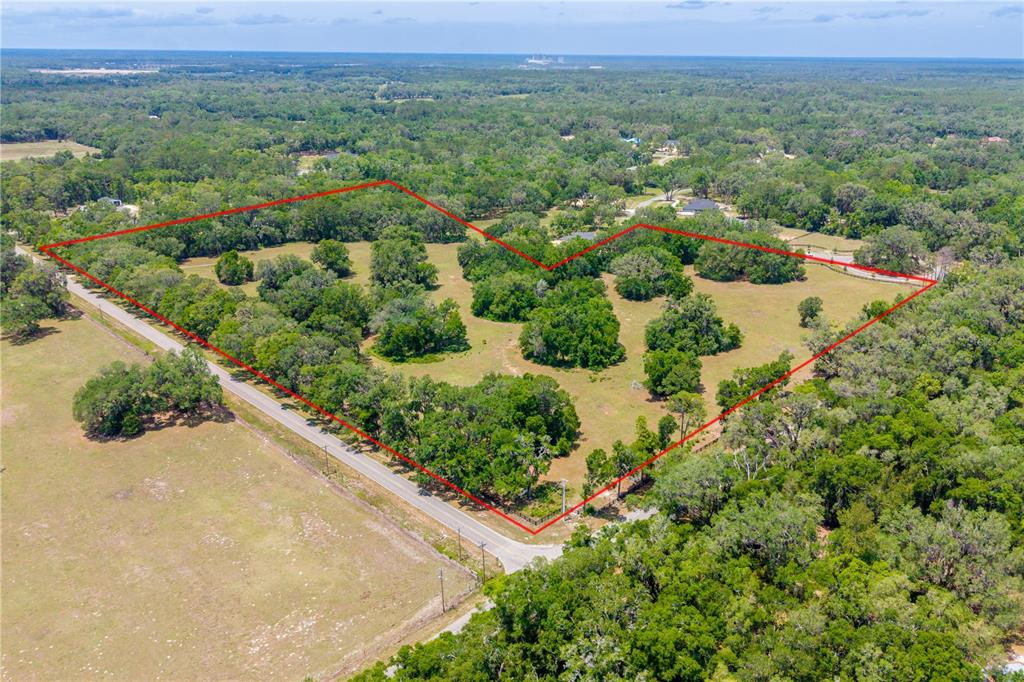 An aerial view shows a large, grassy, tree-filled plot of land outlined in red — TBD SW 170TH STREET, NEWBERRY, FL