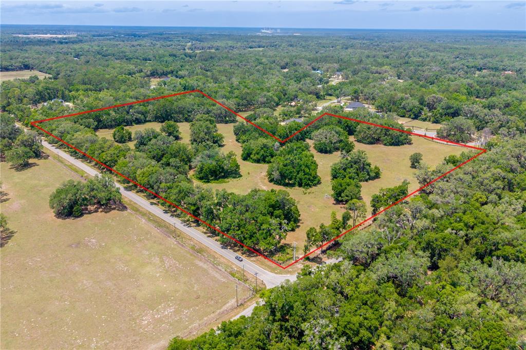 An aerial view shows a large, tree-filled plot of land outlined in red near a road — TBD SW 170TH STREET, NEWBERRY, FL