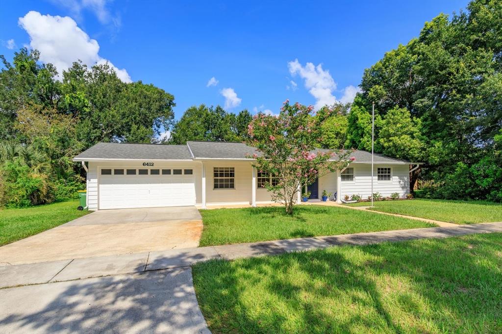 A single-story white house with a two-car garage and a front lawn with trees — 6412 STOCKBRIDGE AVENUE, ORLANDO, FL