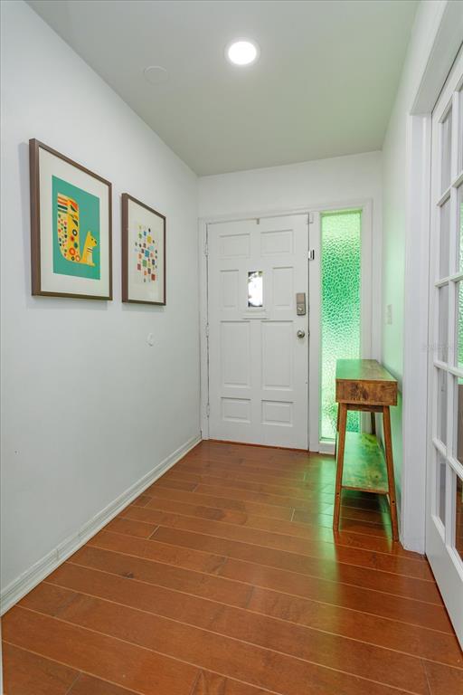 A bright entryway features hardwood floors, a white front door, and two framed wall prints — 6412 STOCKBRIDGE AVENUE, ORLANDO, FL