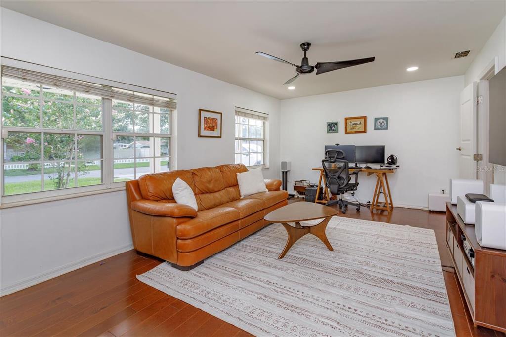 A living room features a leather sofa, a wooden coffee table, and a home office area — 6412 STOCKBRIDGE AVENUE, ORLANDO, FL