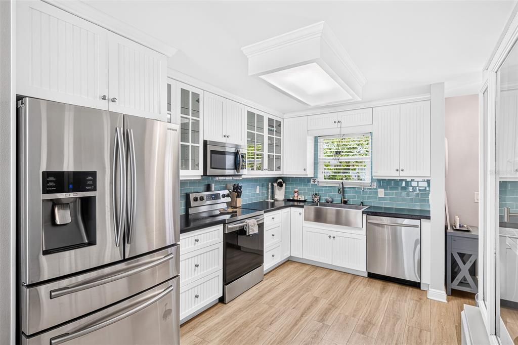A kitchen features white beadboard cabinetry, stainless steel appliances, and a blue subway tile backsplash — 742 LAUREL BAY CIRCLE, NEW SMYRNA BEACH, FL