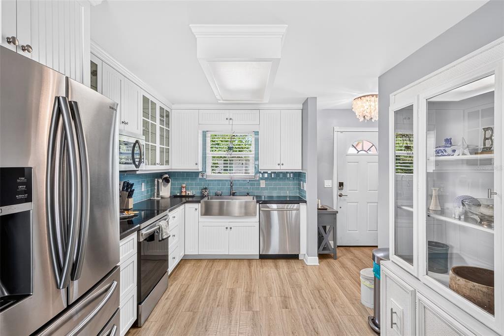 A kitchen features white cabinetry, stainless steel appliances, a farmhouse sink, and blue subway tile — 742 LAUREL BAY CIRCLE, NEW SMYRNA BEACH, FL