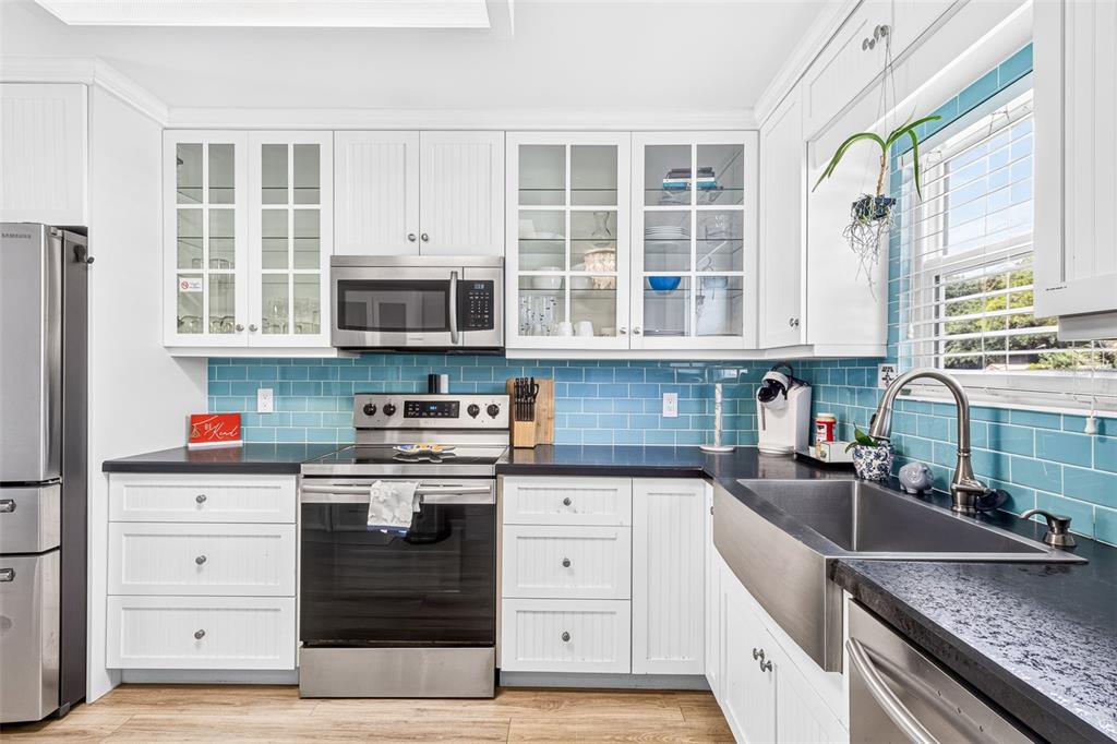 A kitchen features white cabinetry, a blue subway tile backsplash, and stainless steel appliances — 742 LAUREL BAY CIRCLE, NEW SMYRNA BEACH, FL