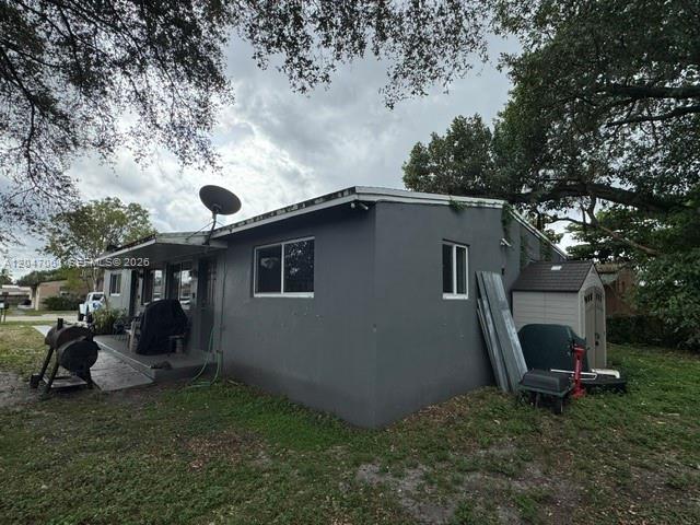 A gray, single-story house exterior features a satellite dish, a small shed, and a grill — 6351 Hayes St, Hollywood FL 33024, HOLLYWOOD, FL