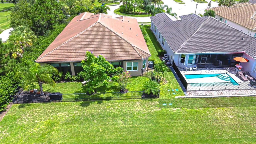 An aerial view shows two adjacent suburban houses with tiled roofs and fenced backyards — 15303 VALENCIA DEL SOL STREET, WIMAUMA, FL