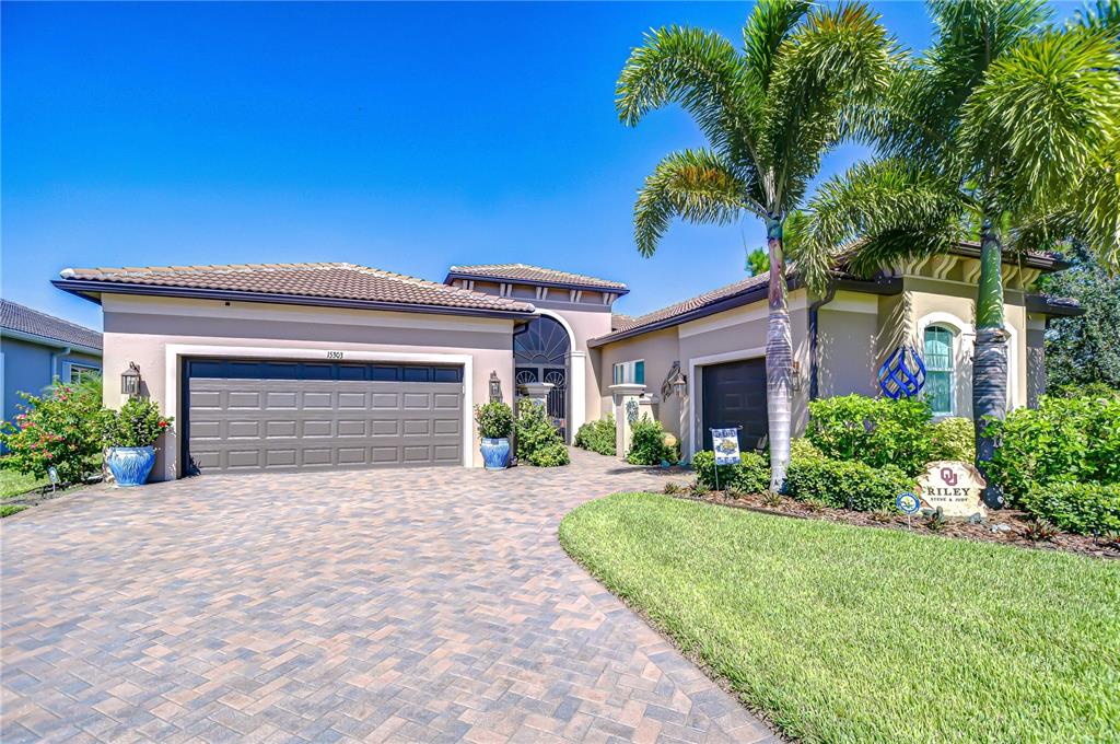 A single-story house with a paved driveway, a three-car garage, and palm trees — 15303 VALENCIA DEL SOL STREET, WIMAUMA, FL