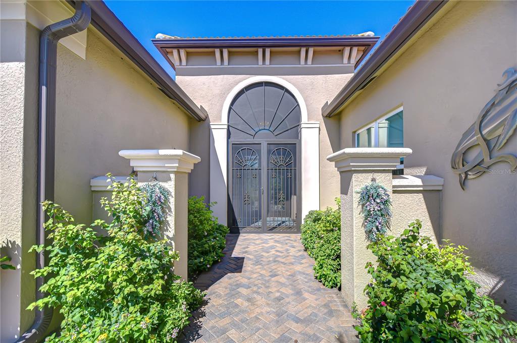 A paved walkway leads to a front entrance with a decorative metal screen door — 15303 VALENCIA DEL SOL STREET, WIMAUMA, FL