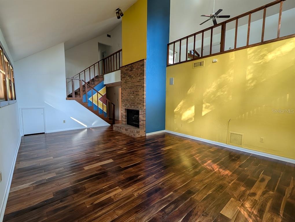 A living room features dark wood floors, a brick fireplace, and a yellow accent wall — 5902 SW 36TH WAY, GAINESVILLE, FL