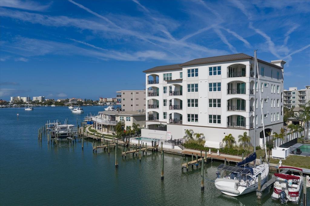 An aerial view of a multi-story waterfront apartment building with boat slips and docked vessels — 211 DOLPHIN POINT UNIT 201, CLEARWATER, FL
