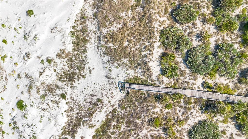 An aerial view shows a wooden boardwalk extending through sandy dunes and coastal vegetation — 2117 OCEAN DRIVE, NEW SMYRNA BEACH, FL