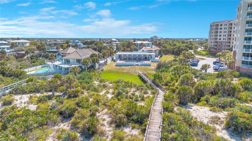 An aerial view shows coastal homes with swimming pools, a wooden boardwalk, and nearby condominiums — 2117 OCEAN DRIVE, NEW SMYRNA BEACH, FL