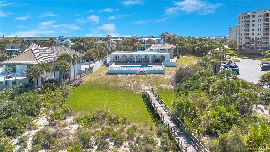 An aerial view shows a coastal property with a pool, lawn, and wooden boardwalk — 2117 OCEAN DRIVE, NEW SMYRNA BEACH, FL
