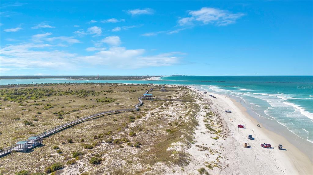An aerial view shows a sandy beach, a wooden boardwalk, and a distant lighthouse — 2117 OCEAN DRIVE, NEW SMYRNA BEACH, FL