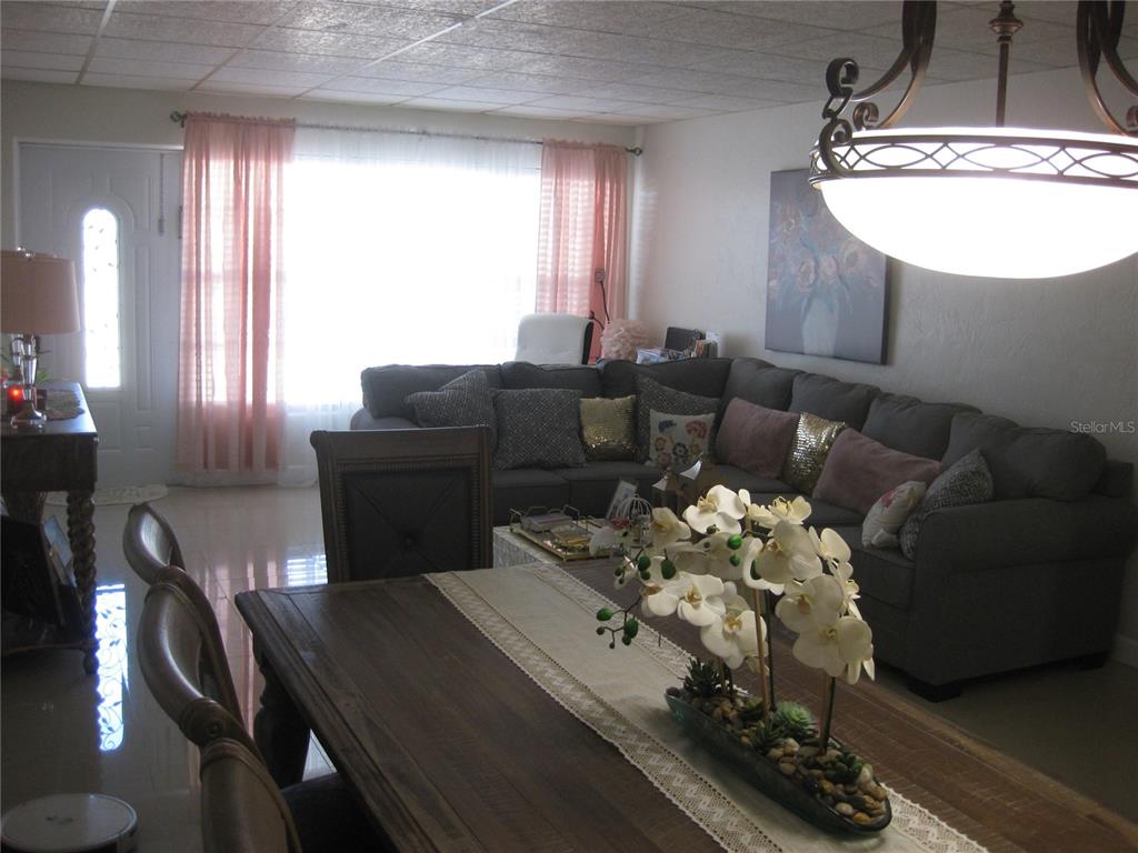 A dining area with a wooden table leads into a living room with a sectional sofa — 5860 43RD TERRACE N UNIT 1518, KENNETH CITY, FL