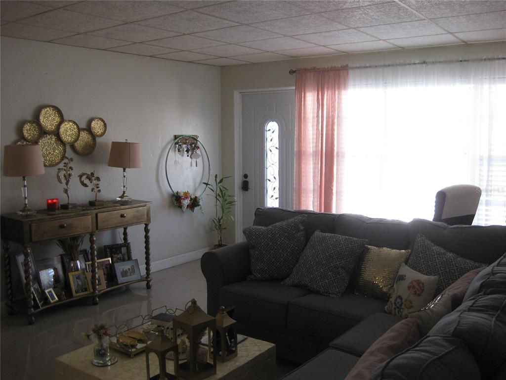 A living room features a grey sectional sofa, a console table, and a front door — 5860 43RD TERRACE N UNIT 1518, KENNETH CITY, FL