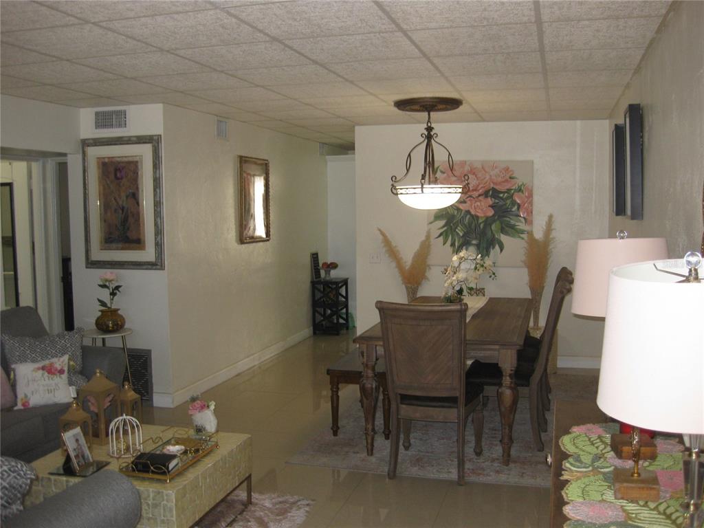 A dining area and living room with tile floors, a drop ceiling, and wooden furniture — 5860 43RD TERRACE N UNIT 1518, KENNETH CITY, FL