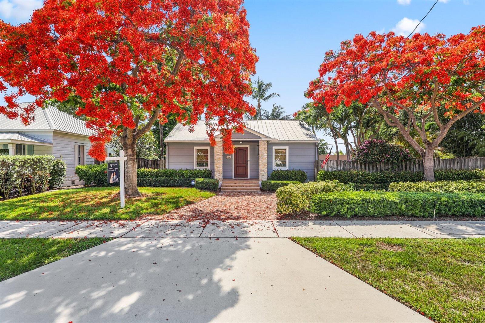 A gray cottage with a metal roof and stone accents sits behind two blooming trees — 304 SE 4th Avenue, Delray Beach FL 33483, DELRAY BEACH, FL