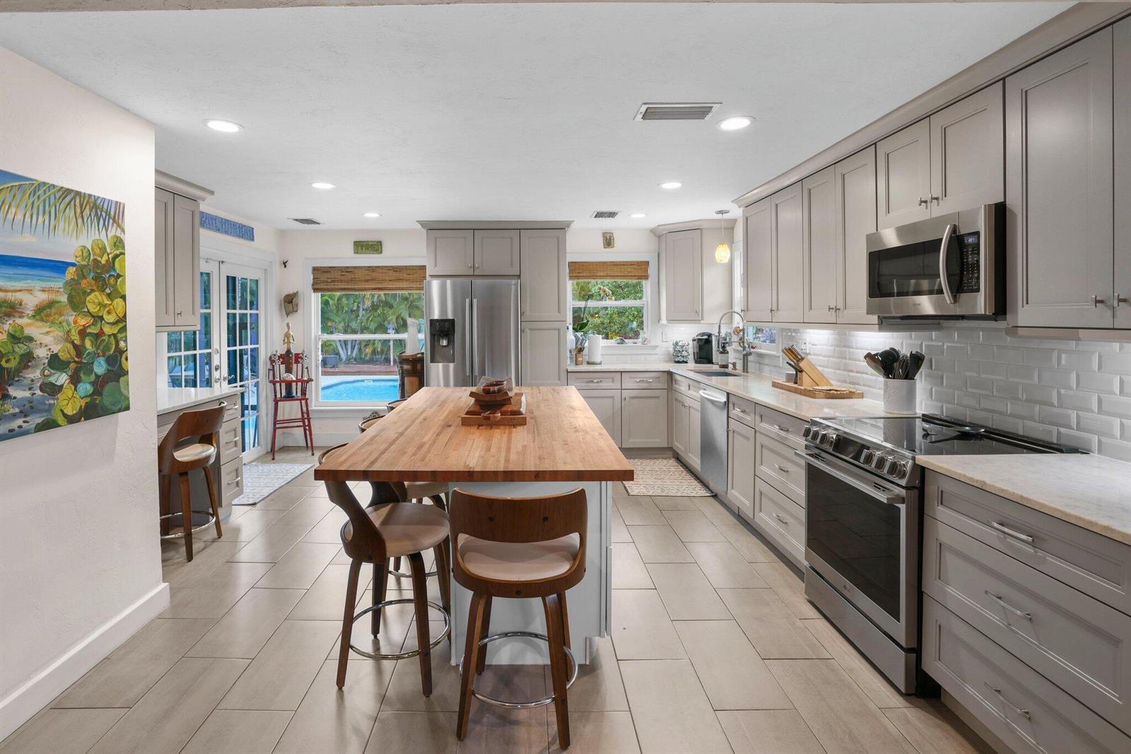 A kitchen with gray cabinets, a wooden island, stainless steel appliances, and a pool view — 304 SE 4th Avenue, Delray Beach FL 33483, DELRAY BEACH, FL