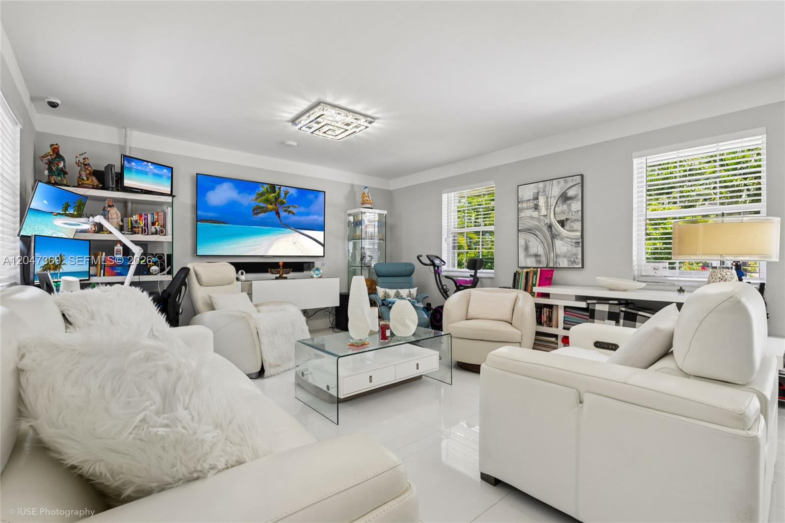 A bright living room features white leather furniture, a glass coffee table, and a television — 3750 Percival Ave, Miami FL 33133, MIAMI, FL