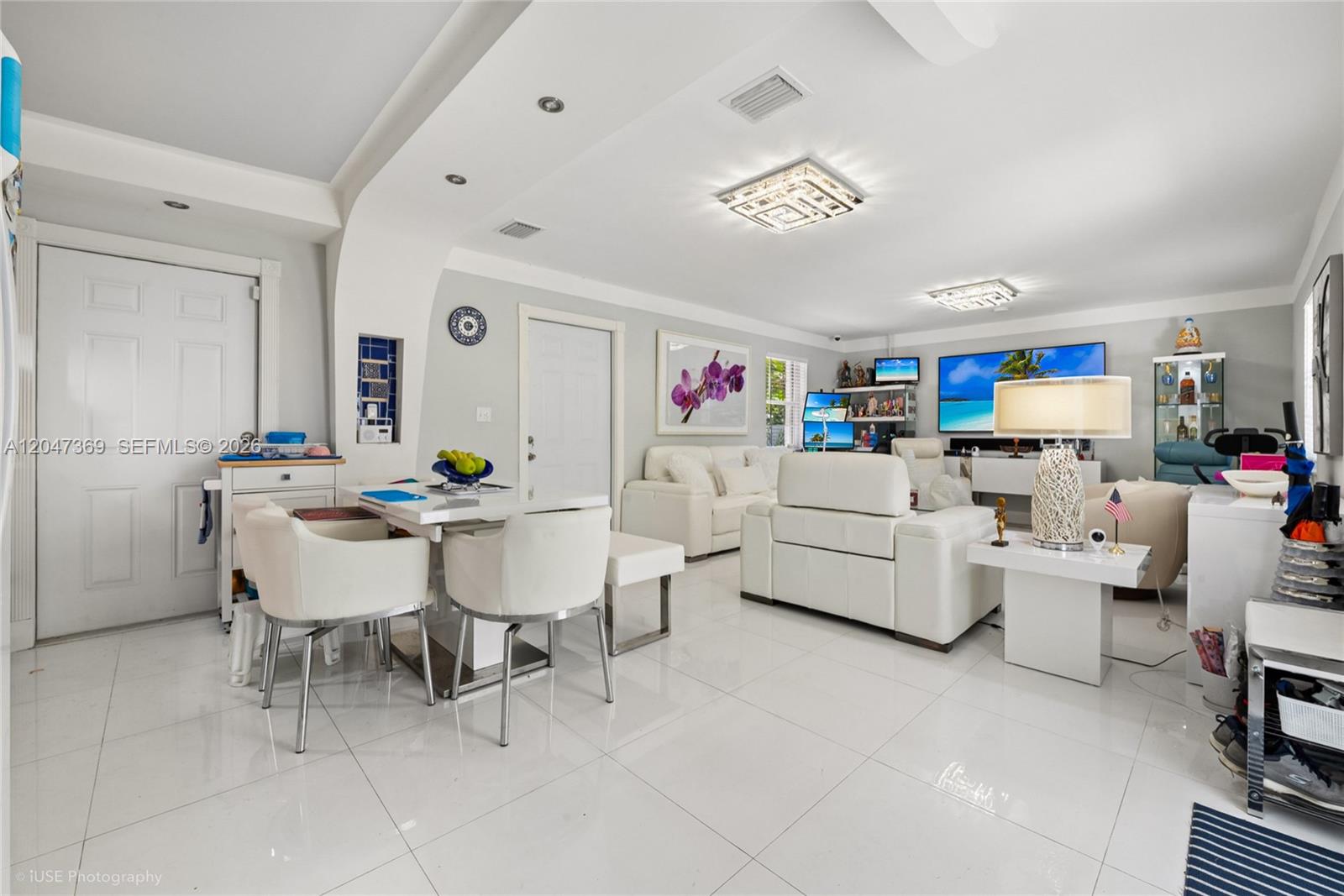 A bright, open-concept living and dining area features white tile flooring and modern furnishings — 3750 Percival Ave, Miami FL 33133, MIAMI, FL