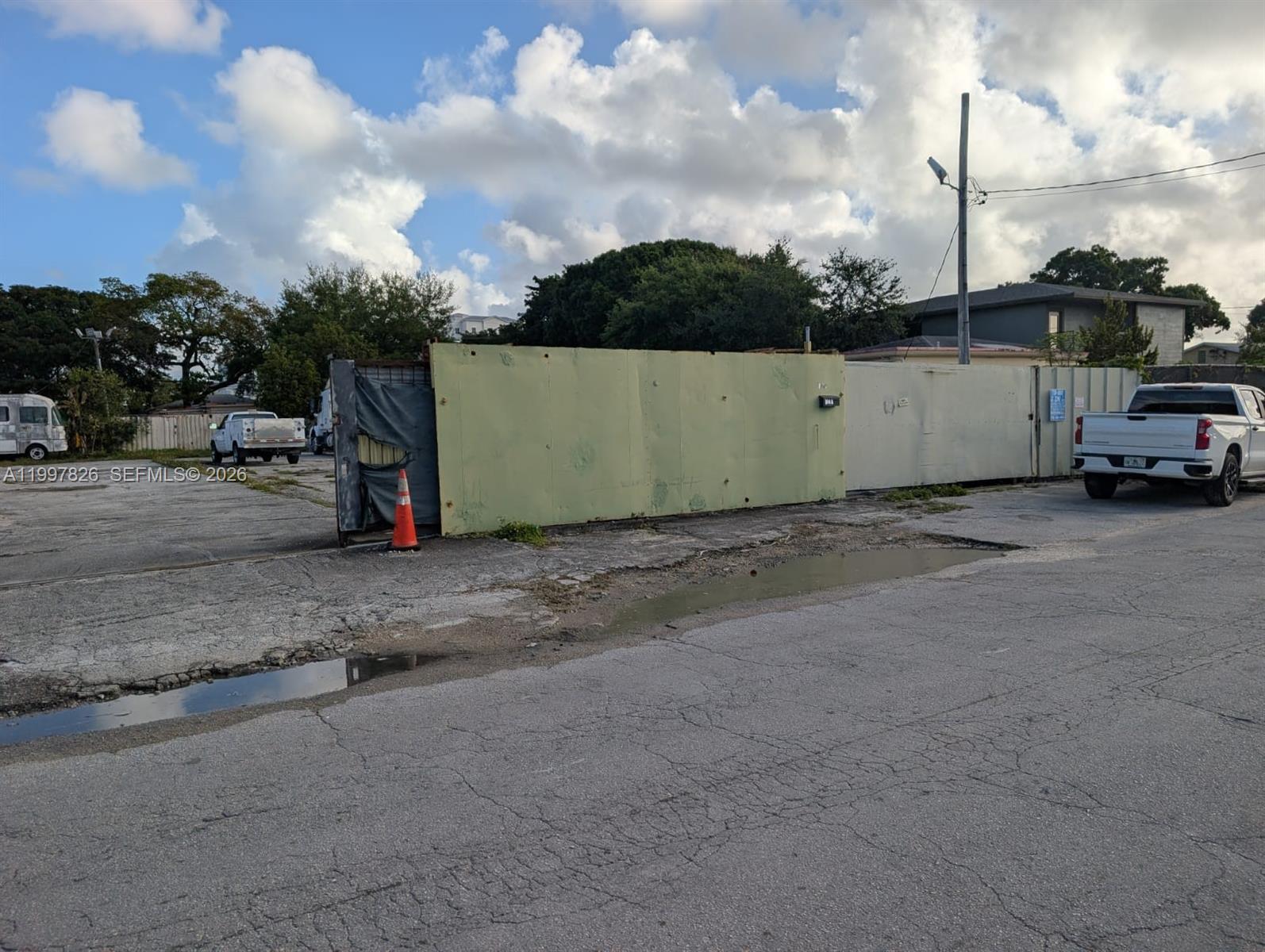 A large green metal fence stands in a paved lot with a white pickup truck — 3175 NW 75TH STREET, Miami FL 33147, MIAMI, FL