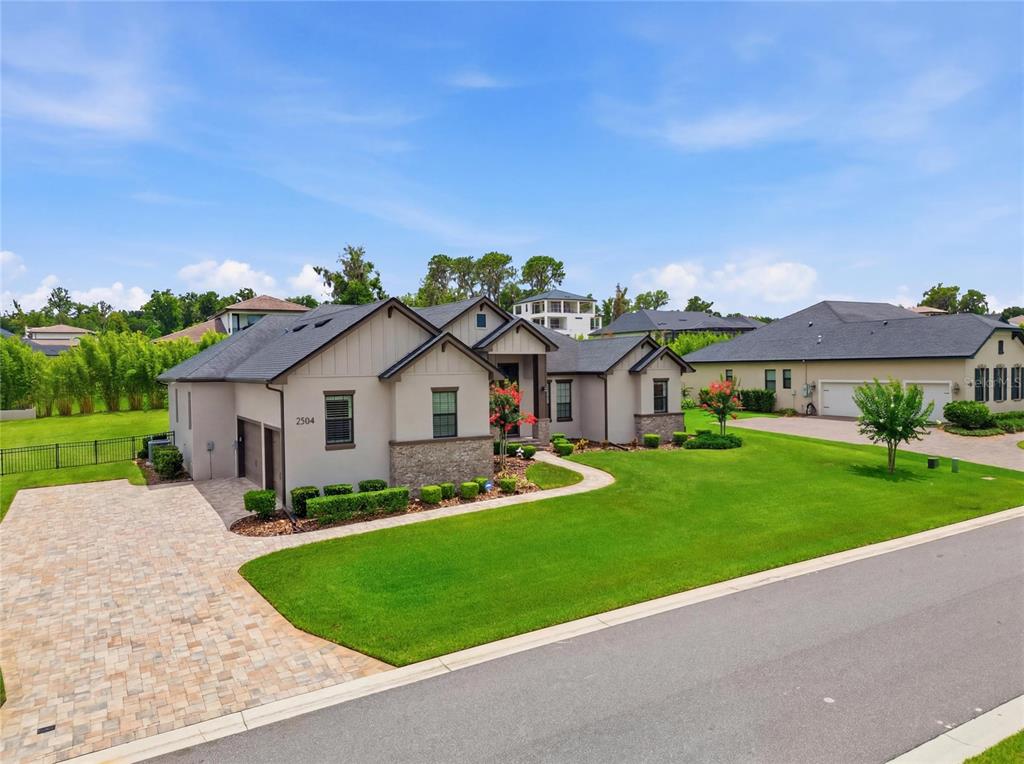 A single-story house with a beige exterior, stone accents, and a paved driveway — 2564 DELPHI WOODS CIRCLE, LAKELAND, FL