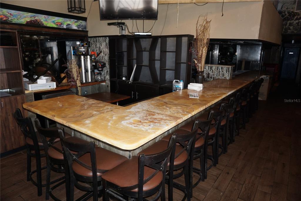 A bar area features a large, light-colored stone countertop with numerous dark wooden bar stools — 5800 34TH STREET N, ST PETERSBURG, FL