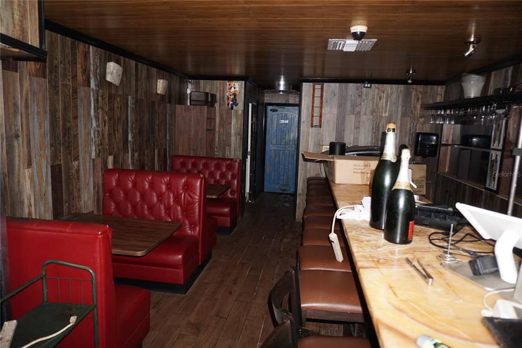 A bar interior features red tufted booths, a wooden counter, and wood-paneled walls — 5800 34TH STREET N, ST PETERSBURG, FL
