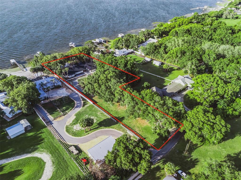 An aerial view shows a large, wooded residential lot outlined in red near a lake — 13061 SE 158TH LANE, WEIRSDALE, FL