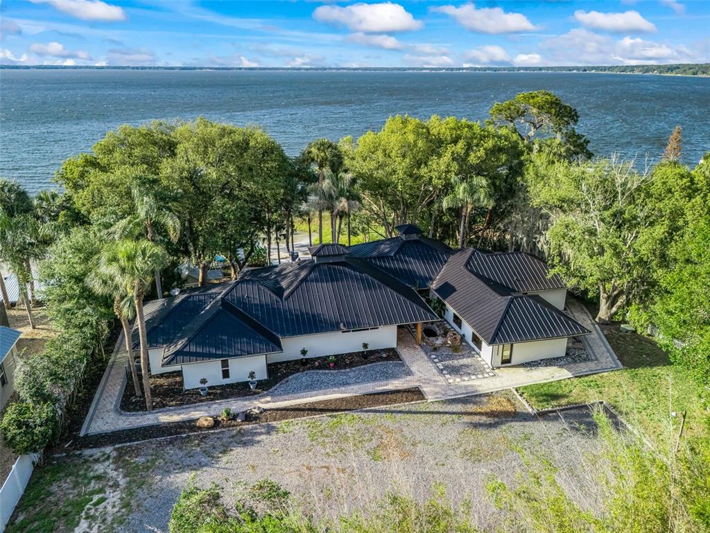 An aerial view of a white house with a black metal roof near a lake — 13061 SE 158TH LANE, WEIRSDALE, FL