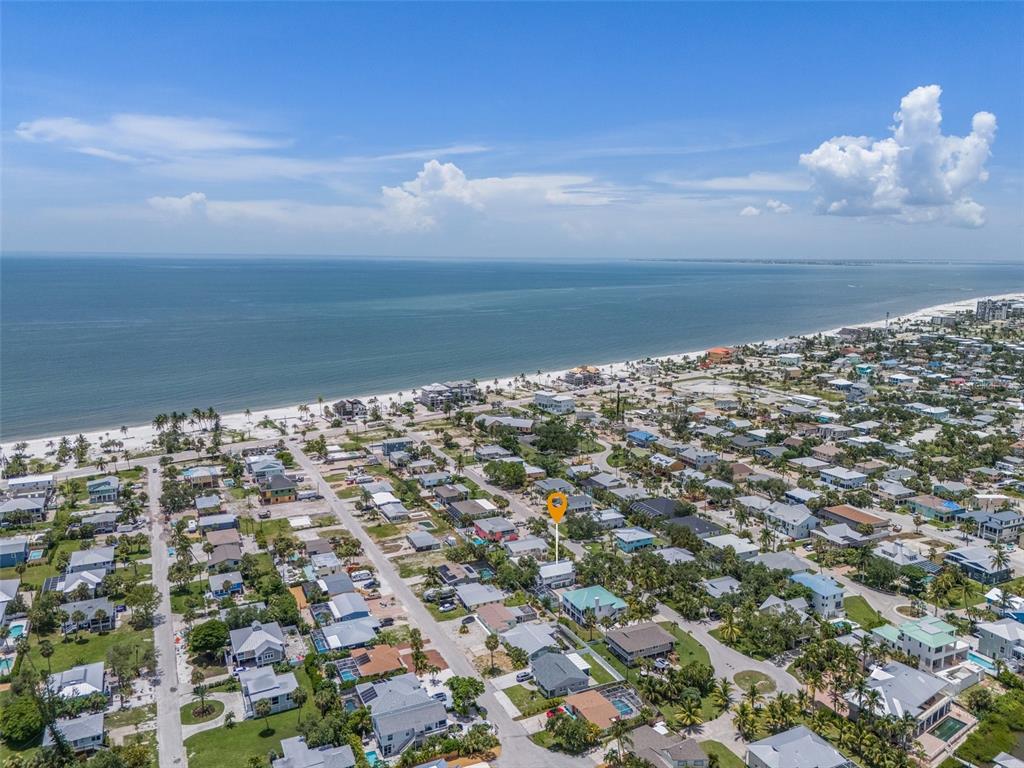 An aerial view shows a coastal neighborhood with a highlighted house near the beach — 140 BAY MAR DRIVE, FORT MYERS BEACH, FL