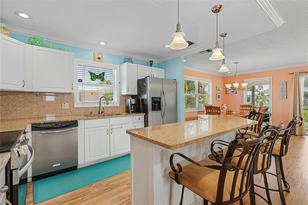 A kitchen features white cabinets, granite countertops, stainless steel appliances, and a breakfast bar — 140 BAY MAR DRIVE, FORT MYERS BEACH, FL