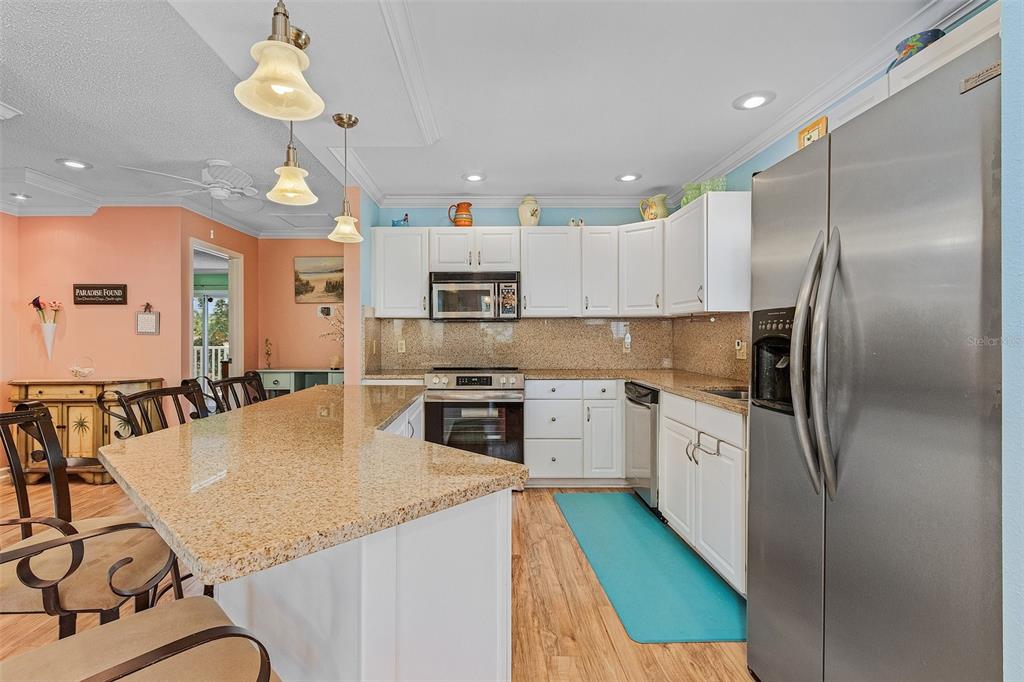 A kitchen features white cabinets, granite countertops, stainless steel appliances, and a breakfast bar — 140 BAY MAR DRIVE, FORT MYERS BEACH, FL