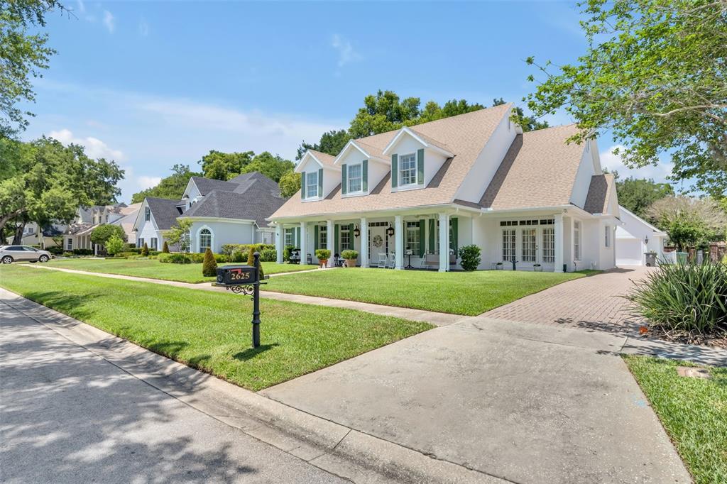 A white two-story house with green shutters and a large front lawn under a blue sky — 2625 PARK PLACE DRIVE, WINTER PARK, FL