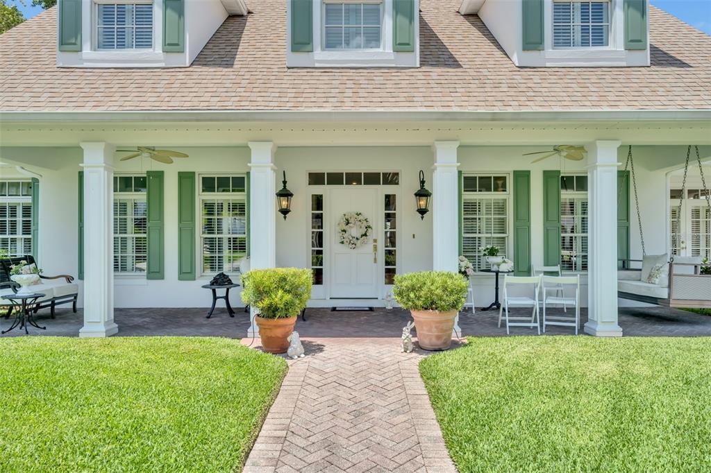 A white house with green shutters features a front porch with a brick walkway — 2625 PARK PLACE DRIVE, WINTER PARK, FL